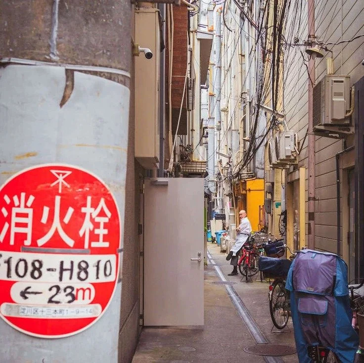 narrow street in Osaka with bicycles and electric wires, captured during slow travel.