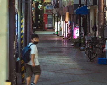 A child walking in a neon-lit alley in Tokyo at night, captured during a street photography