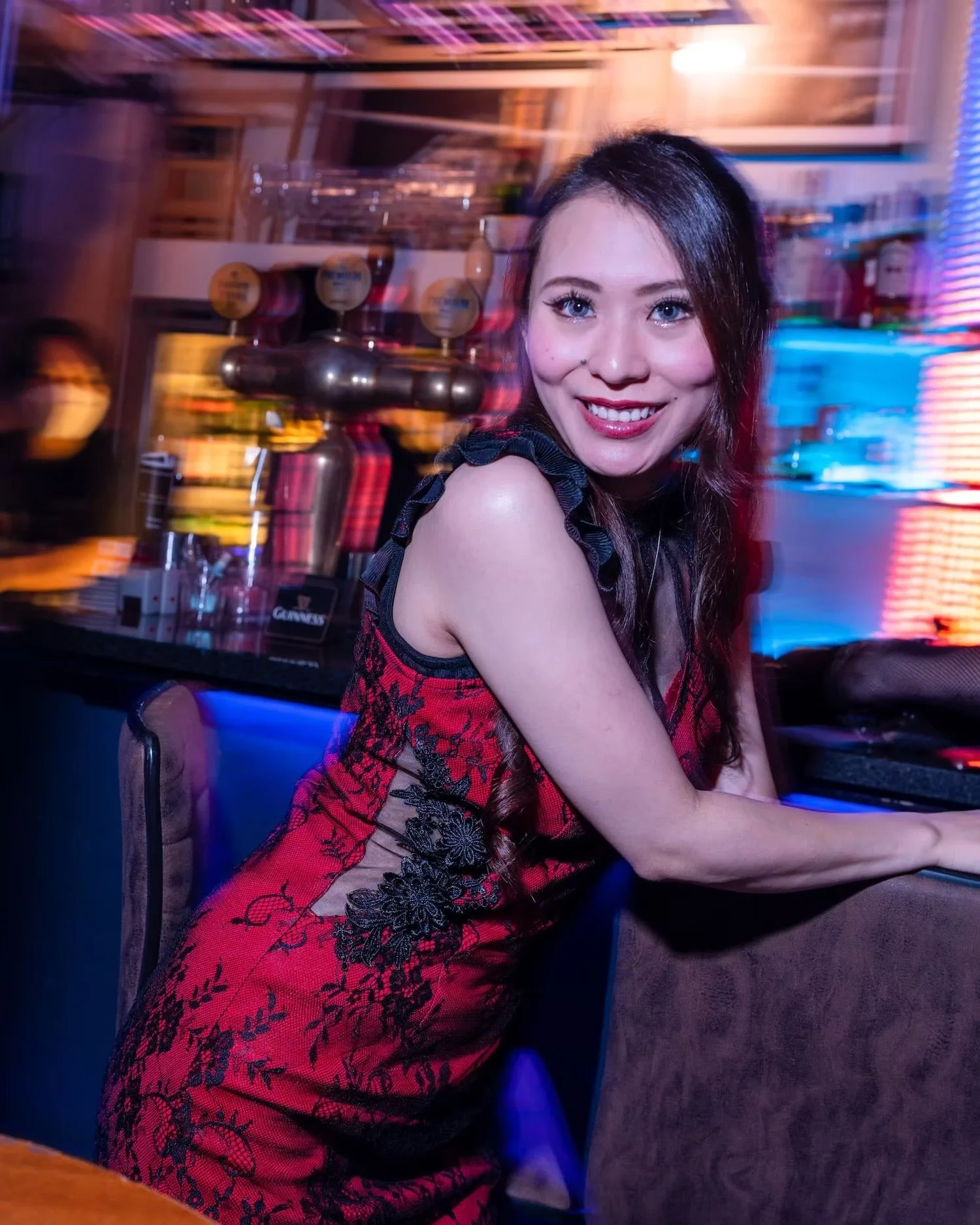 Smiling Woman in a Red Lace Dress at a Bar