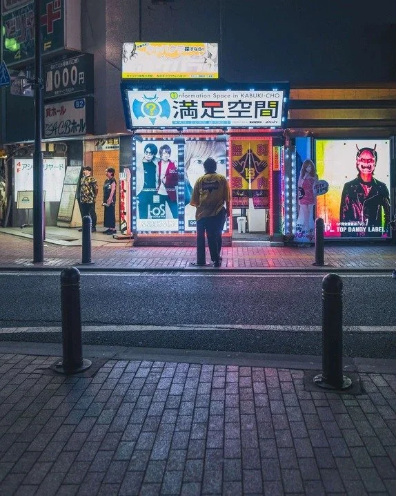 Pedestrians walking in front of neon-lit shops in Kabukicho, captured with an ultra-wide lens.