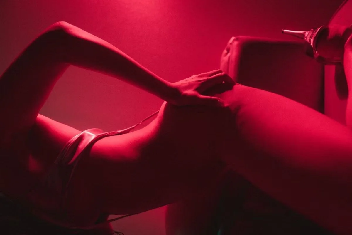 A woman in lingerie lying down under deep red lighting, creating a dramatic silhouette. Boudoir Photography by Tokyo Photographer Deniz Demir. Japan.