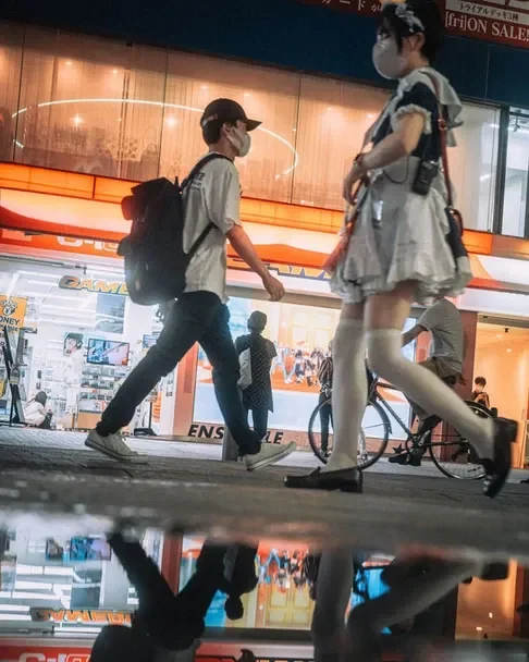A person passing by a window with a cute anime character, snapped during a Tokyo street photography workshop.