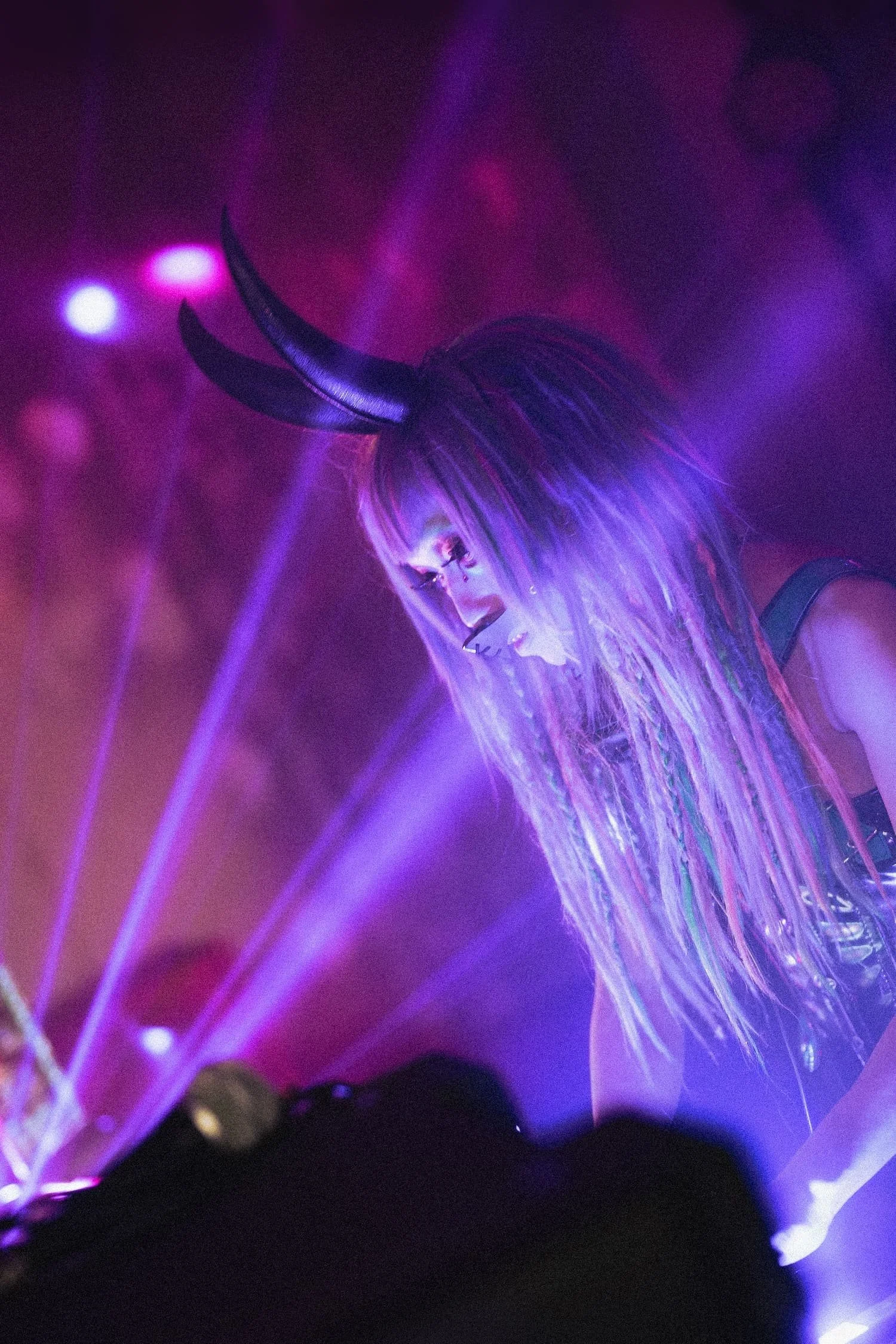 Bondage Ball 
---
A person wearing a black horned headpiece with colorful lighting effects in the background.