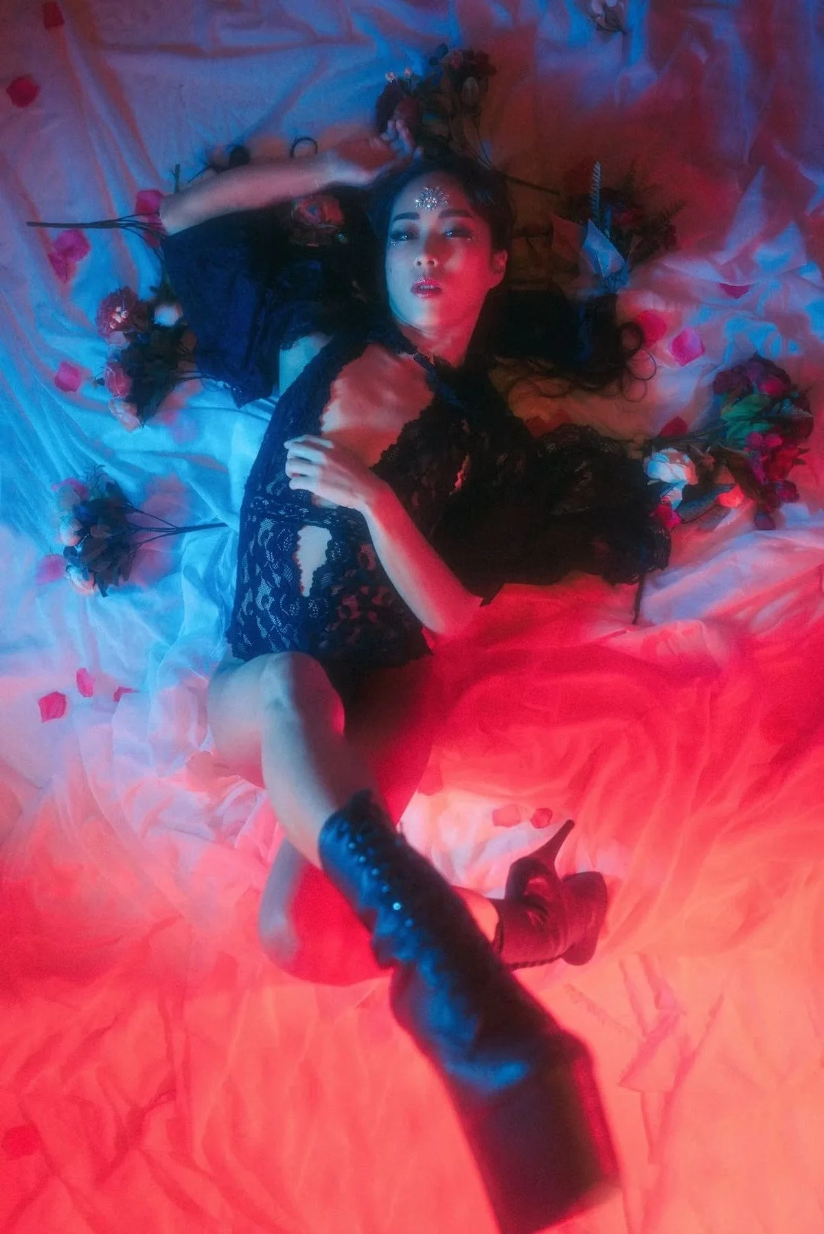 A model reclines dramatically in a vibrant blue and red cyberpunk-inspired setting. The dramatic lighting and futuristic styling add to the edgy, sci-fi feel.