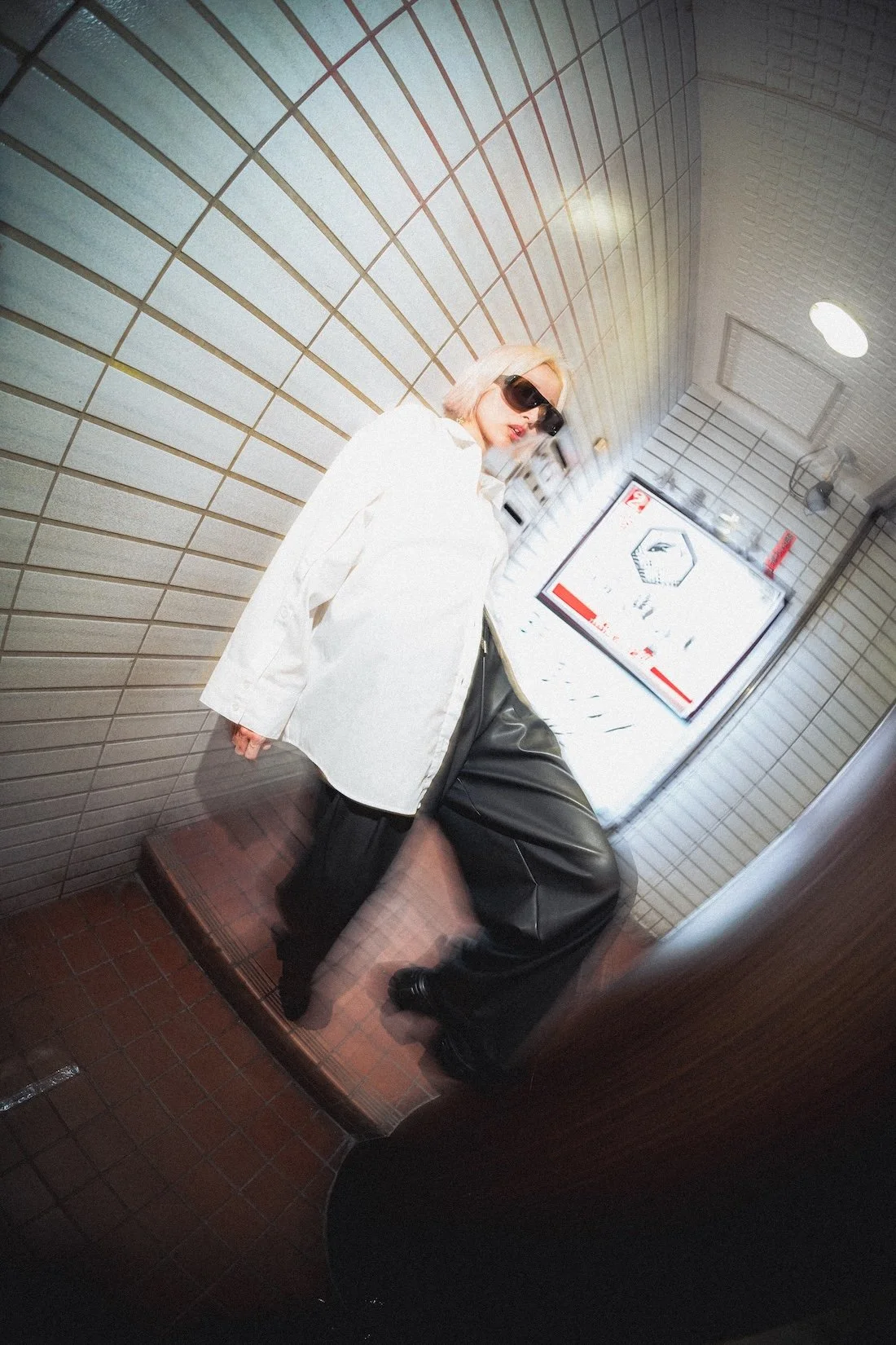Vasuma Eyewear
---
A woman wearing sunglasses, a white shirt, and black leather pants taking a mirror selfie in a tiled bathroom or elevator. Editorial photographer Deniz Demir.
