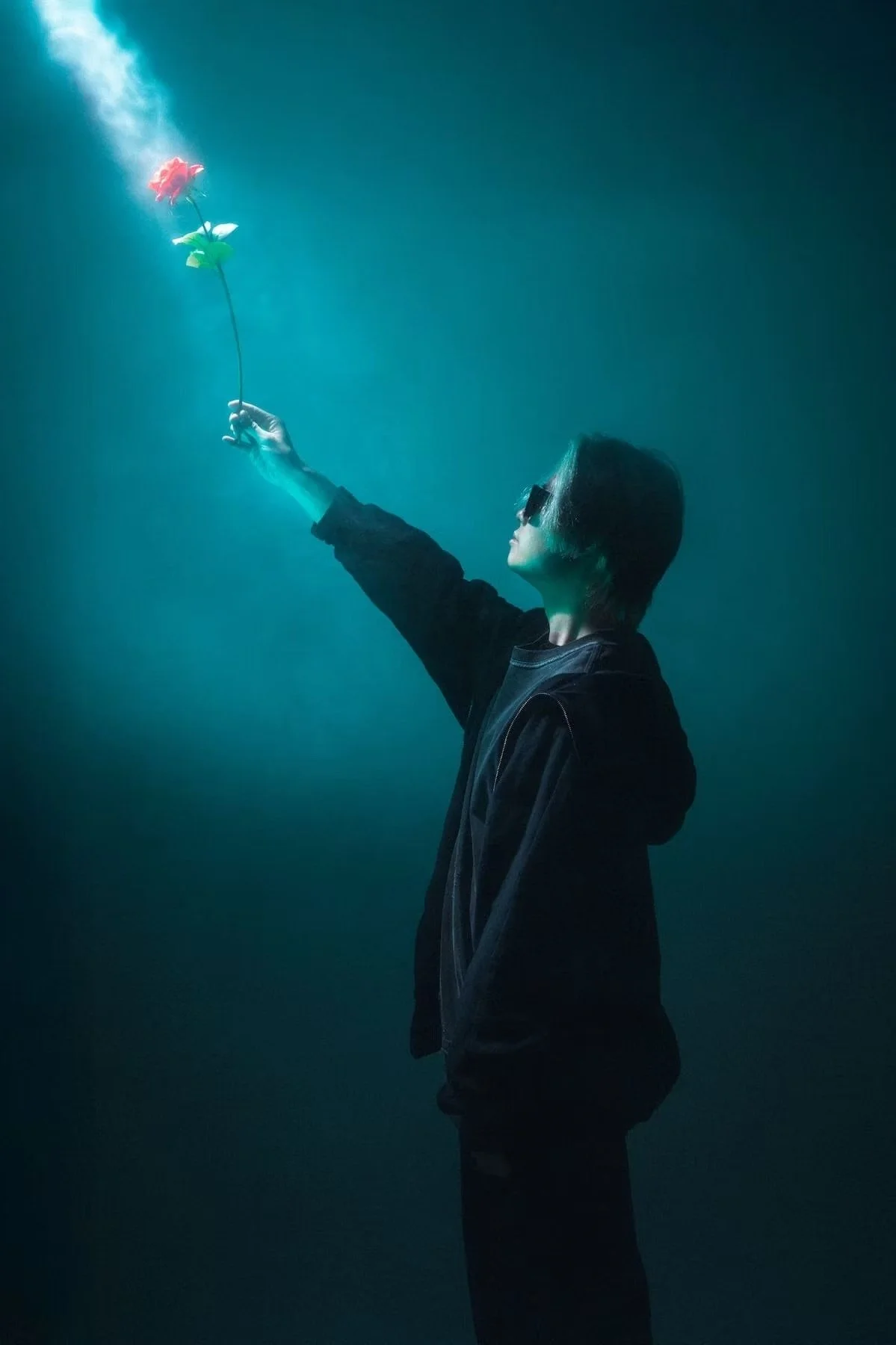 Creative shoot with model holding a flower into a light coming from the corner at Tekumi Studios with haze