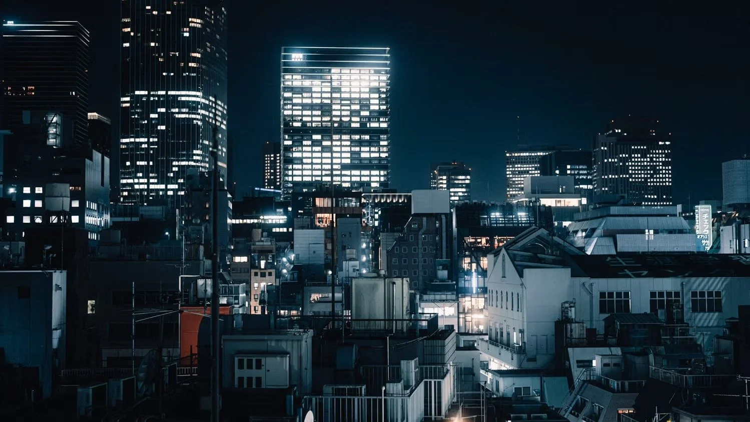 Night view of a city skyline with illuminated skyscrapers and buildings in a futuristic setting.