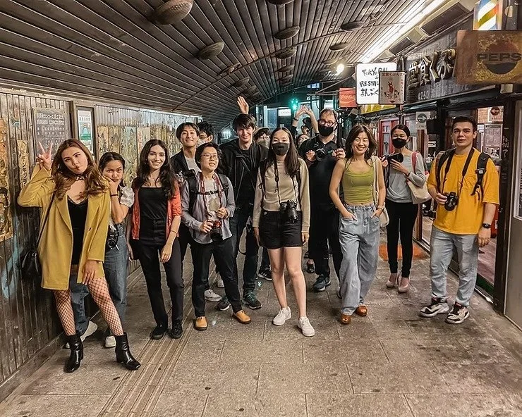Group photo of participants posing for a picture during the Tekumi Photowalks street photography workshop in a vibrant Tokyo alley.