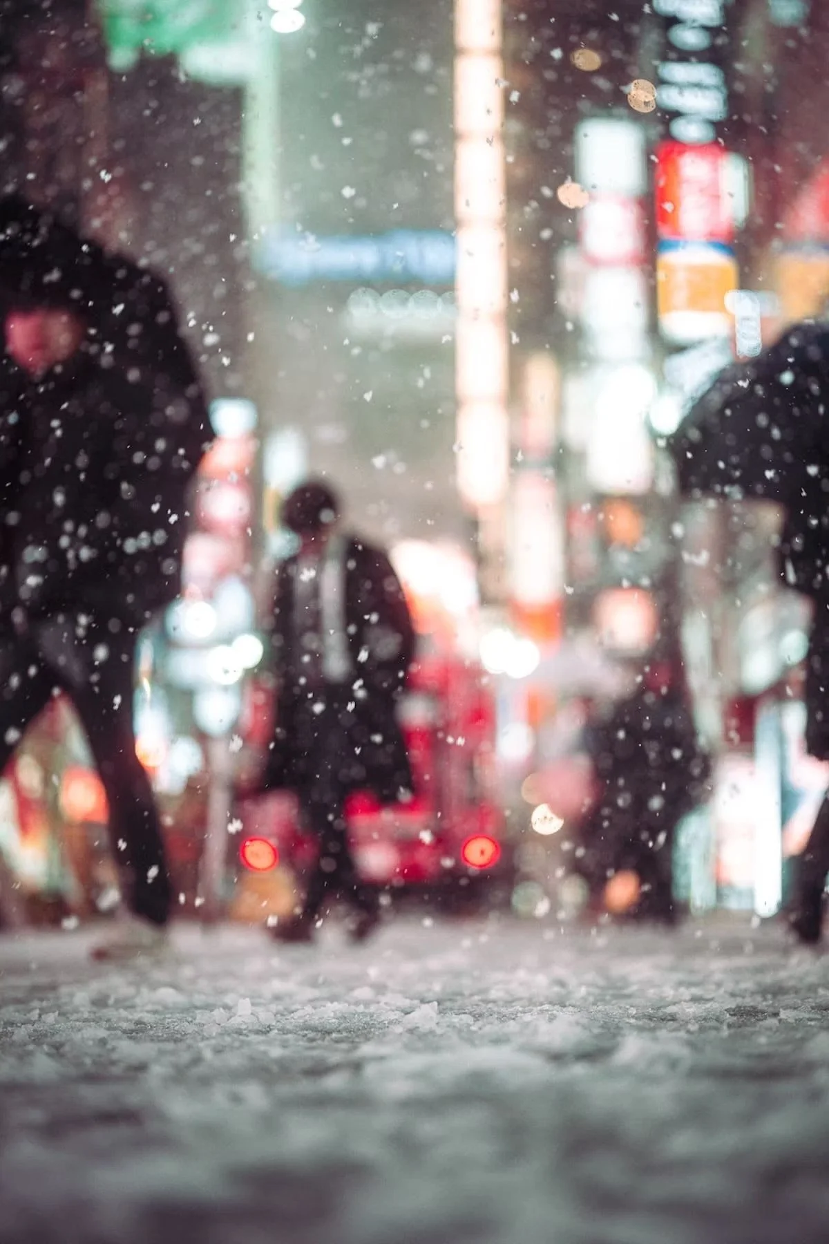 People walking on a city street during a rainstorm, with water droplets on the windshield and blurry colorful city lights in the background in Kabukicho Shinjuku Tokyo shot by Tokyo street photographer Deniz Demir.
