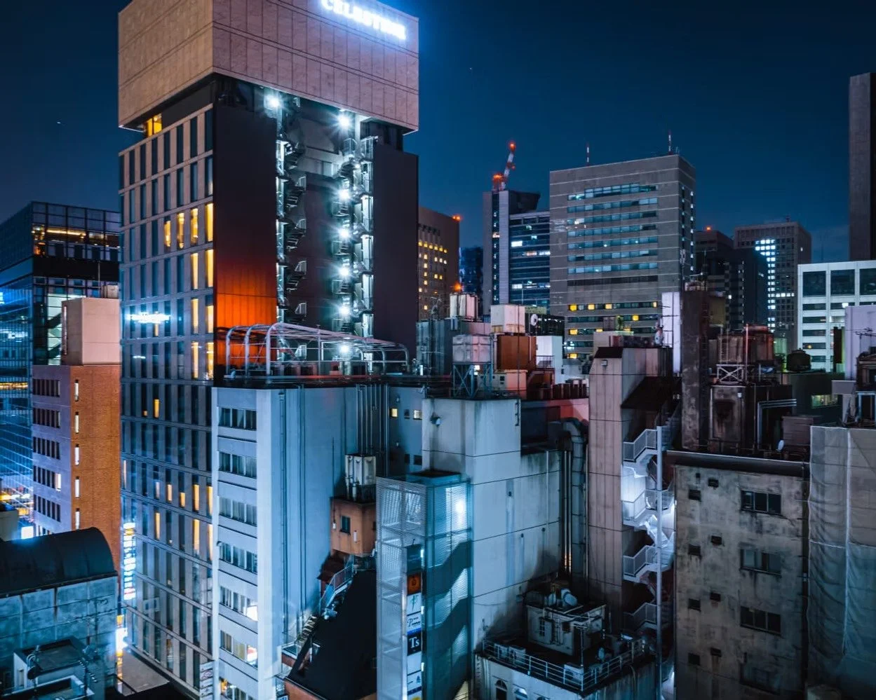 Nighttime cityscape with illuminated high-rise office buildings and skyscrapers in a modern urban area.