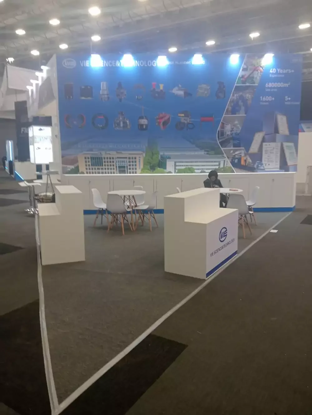 Stand tecnológico con gran pantalla digital azul, mobiliario moderno y espejos para amplitud visual.