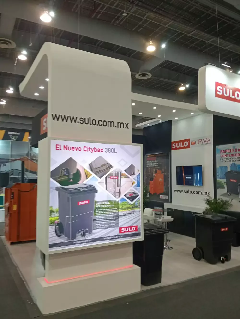 Stand con gráficos informativos en español resaltando soluciones ecológicas para manejo de desechos.