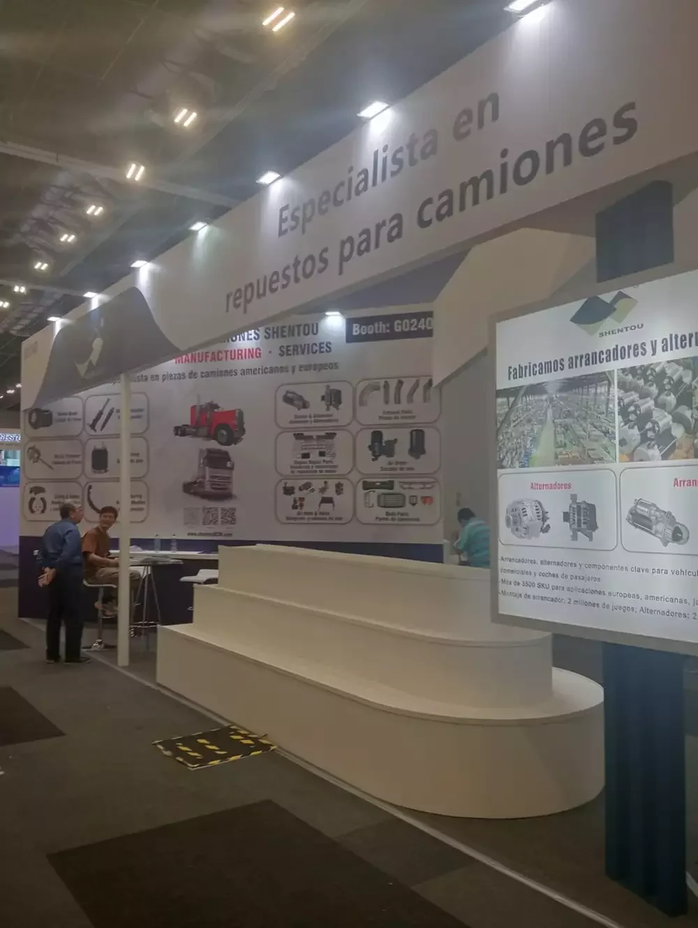 Stand tipo península con mostrador curvo de recepción y gráficos de gran formato para el sector transporte.