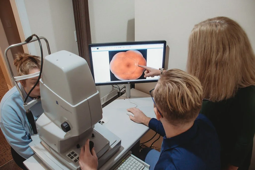 Medical professionals examine a retinal scan on a computer screen during eye examination.