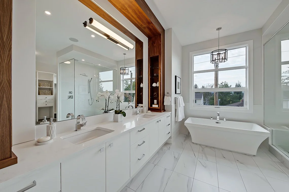 Modern bathroom with double vanity, large mirror, walk-in shower with glass door, and freestanding bathtub near window.