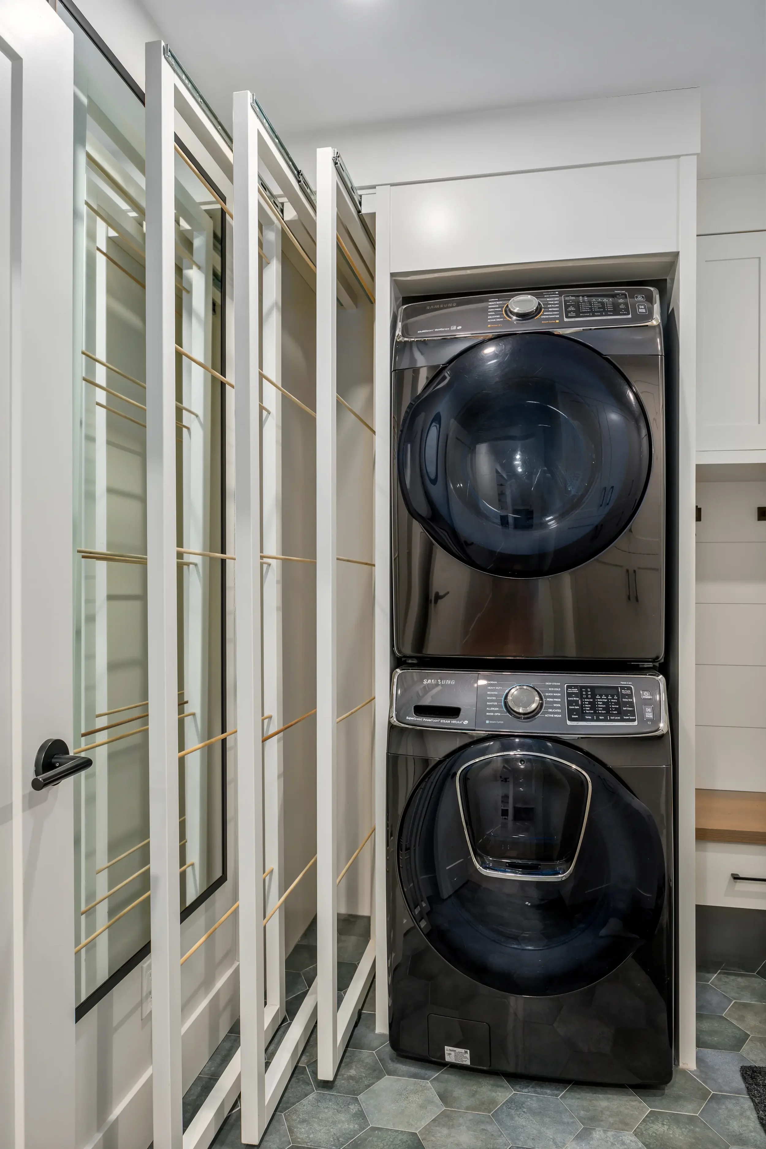 Stacked front-loading Samsung washing machines in a laundry room.