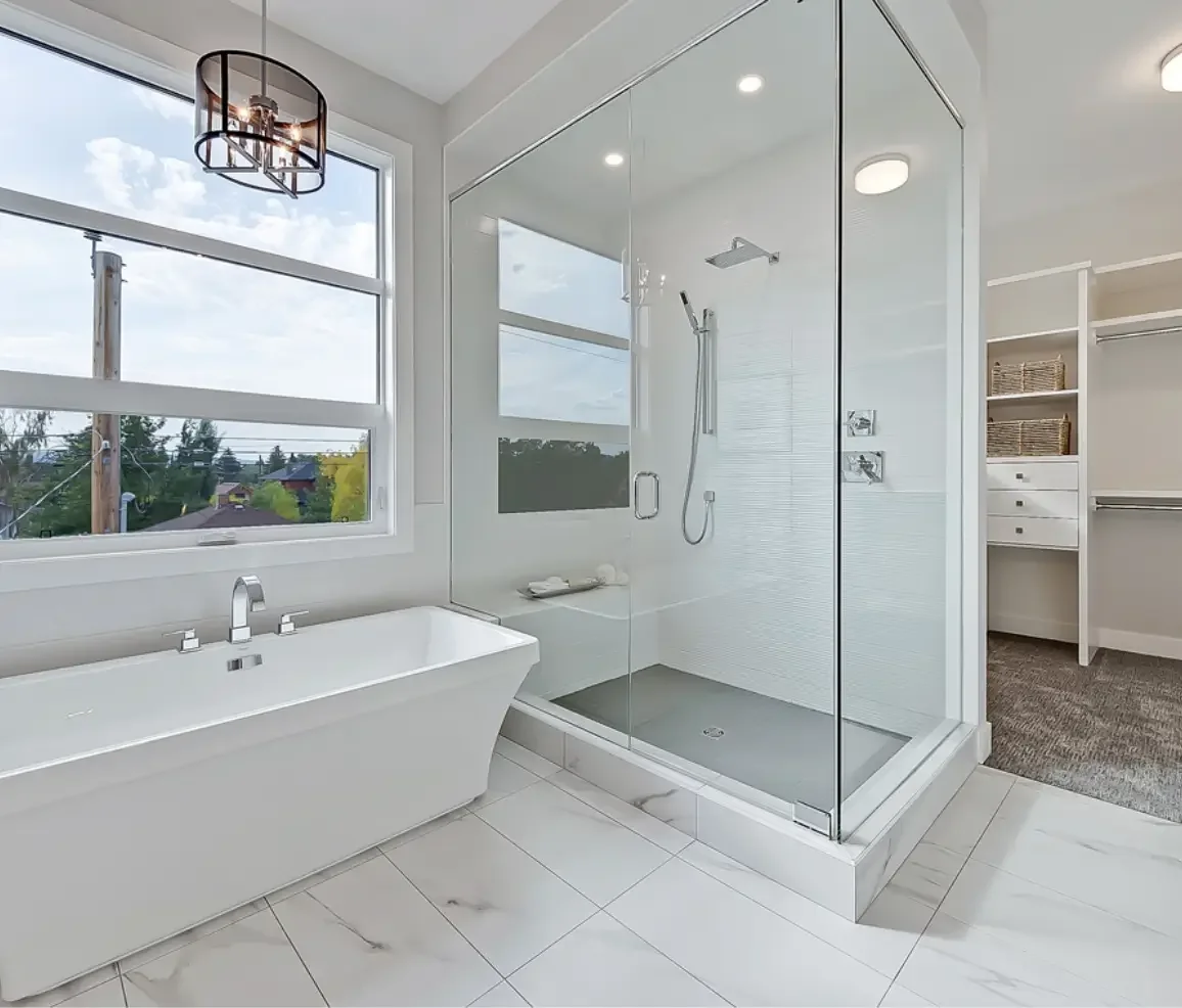 Modern bathroom with a large window, white bathtub, glass-enclosed shower, and a walk-in closet with baskets and drawers.