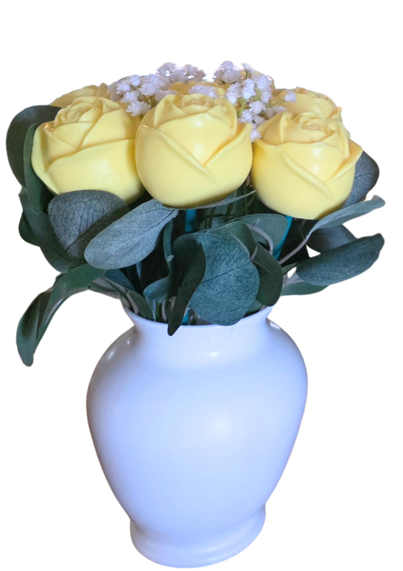 A white vase containing a bouquet of yellow roses and green leaves.