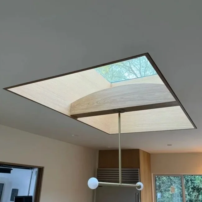 Modern interior ceiling with a square skylight and a suspended light fixture with two white globes.