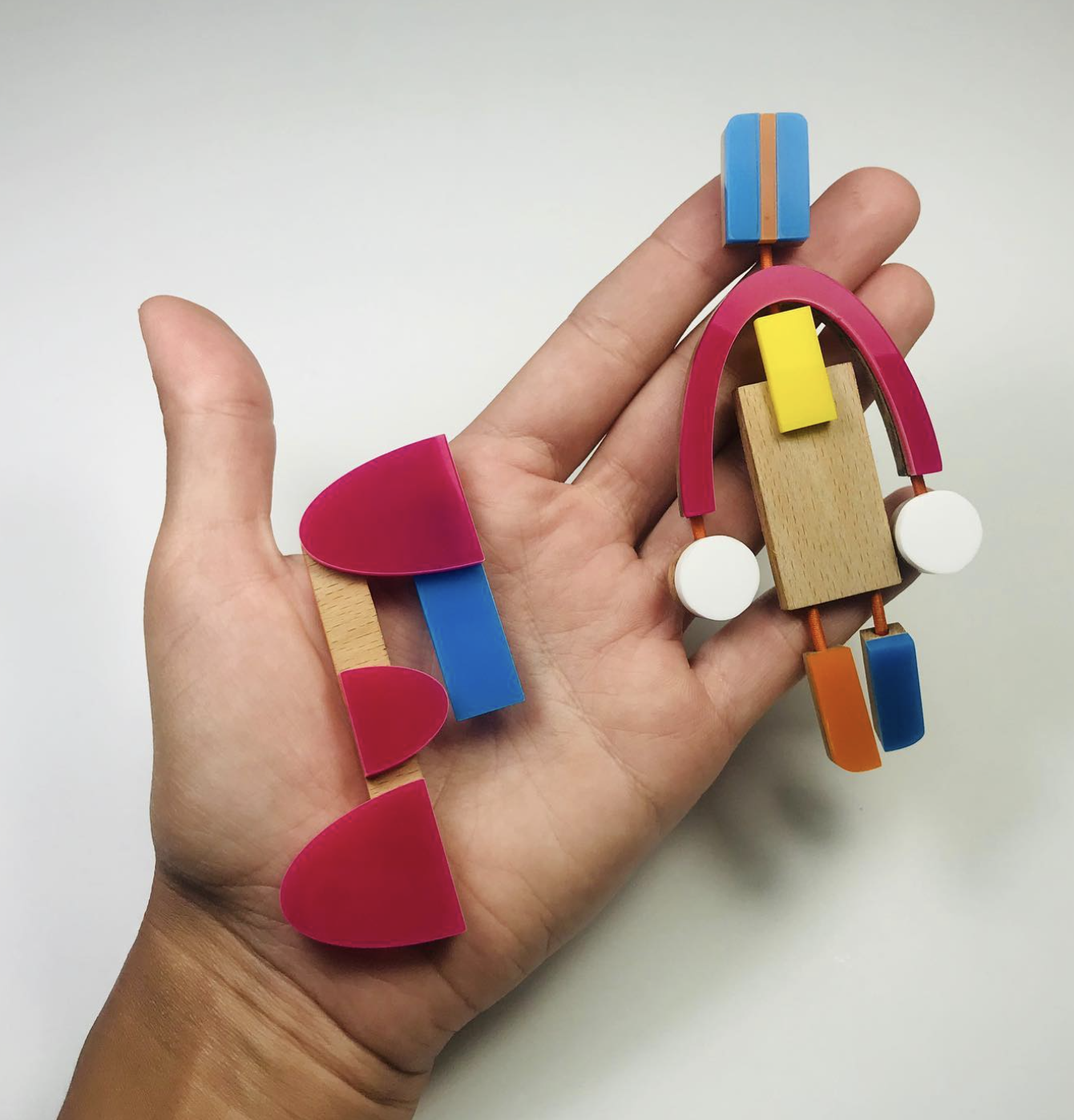 Hand holding colorful abstract wooden toy with various geometric shapes and colors.