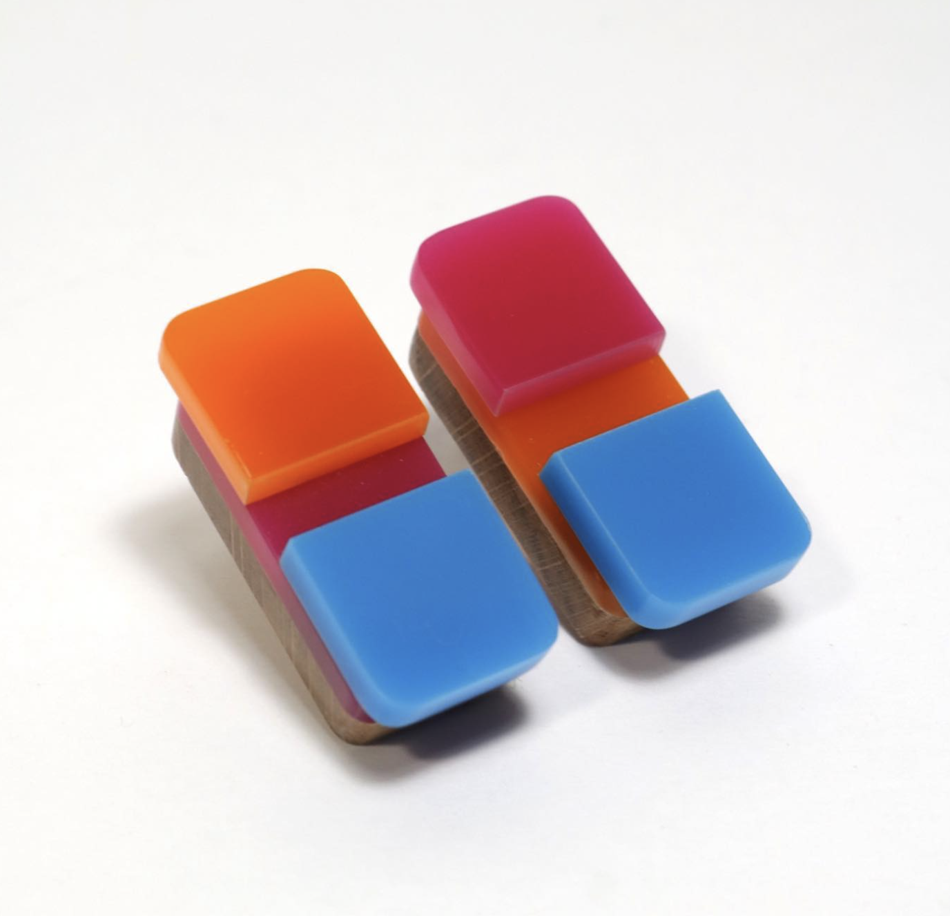 Two wooden and plastic puzzle pieces with colorful blocks on top, white background