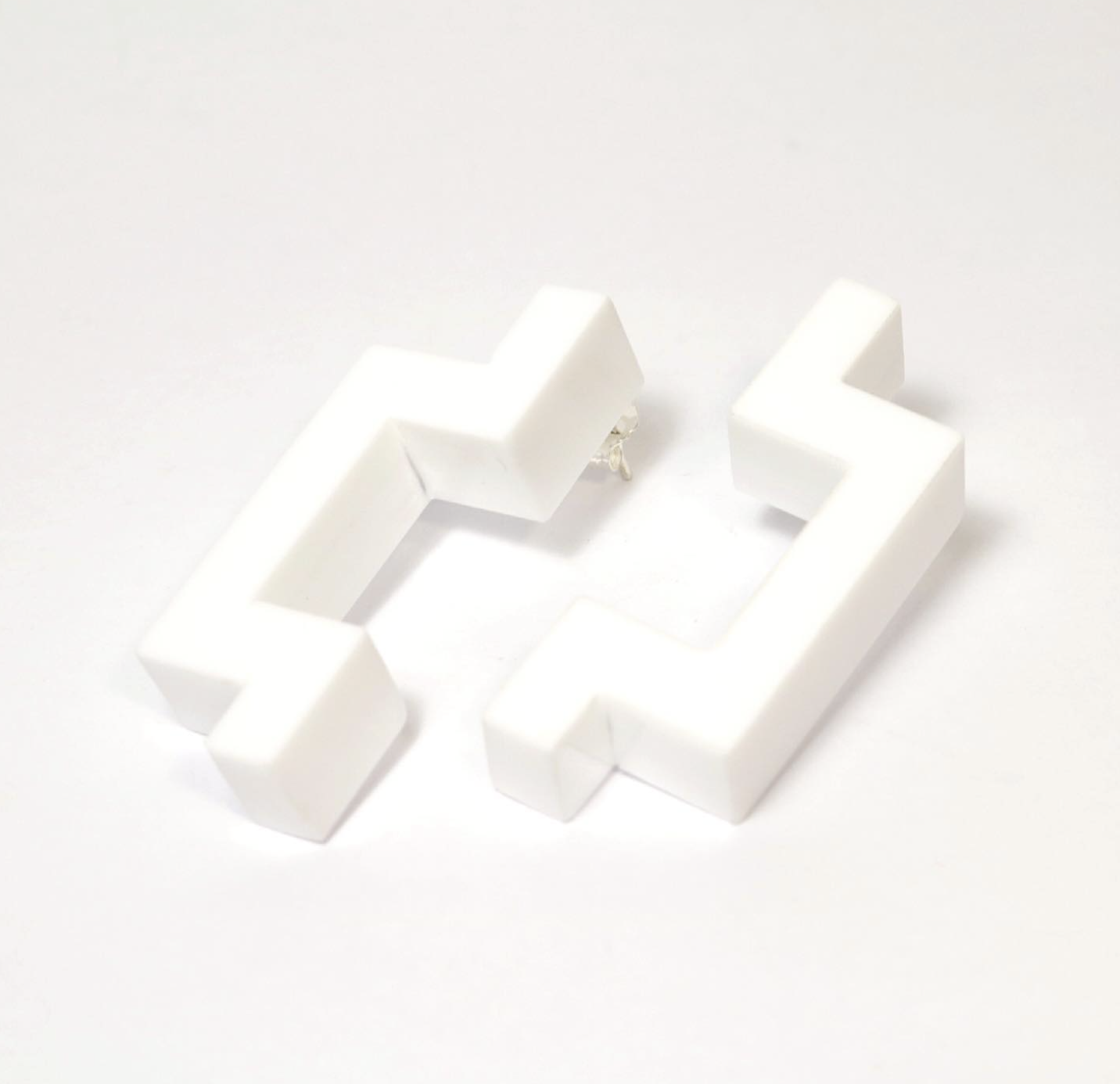 White 3D printed or molded plastic lowercase letters 'c' and 's' arranged on a white surface.