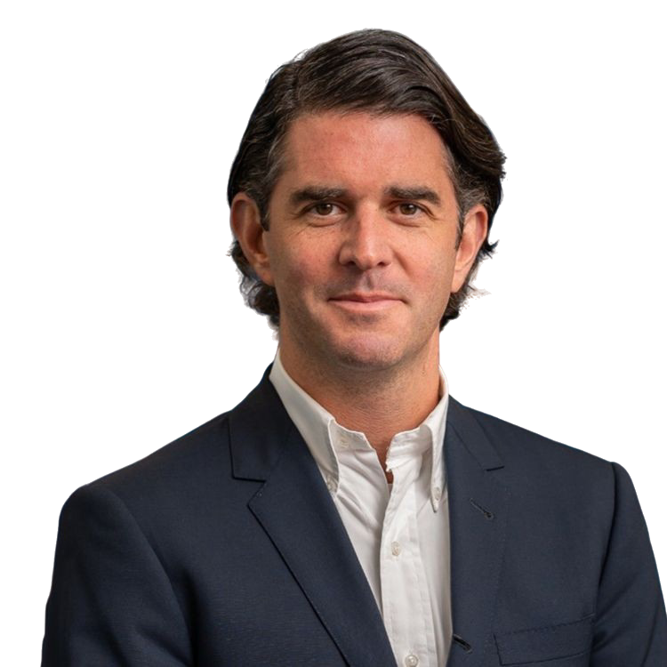 A man with medium-length brown hair wearing a dark blazer and a white collared shirt.