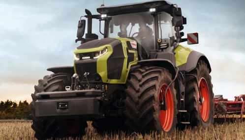 Large green and black tractor with red wheels working in a field during daytime.