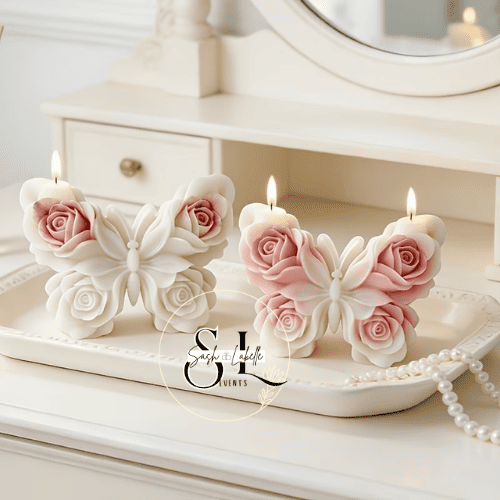 Decorative butterfly-shaped candles with pink and white roses, lit, placed on a white tray on a vintage dresser.