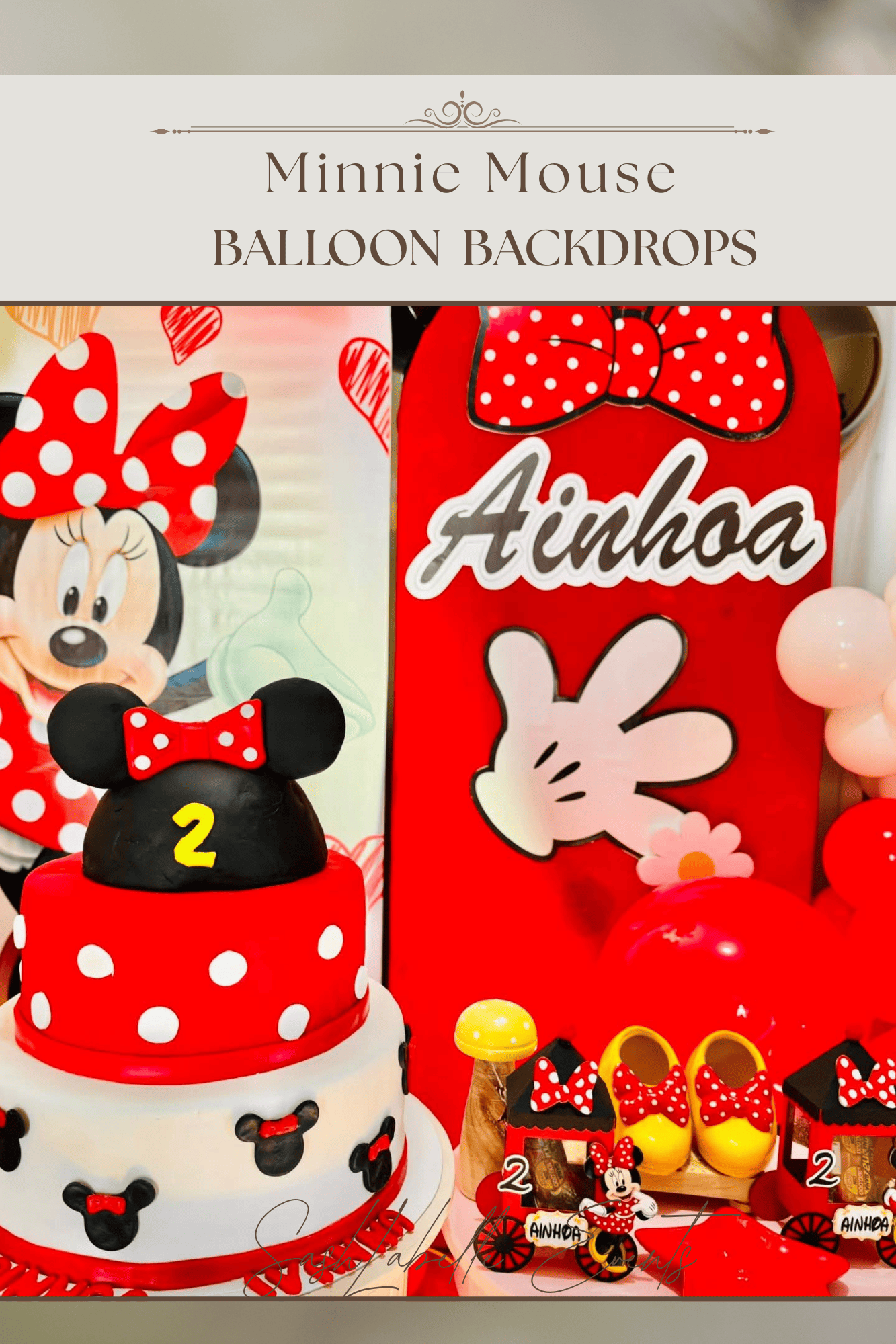 A Minnie Mouse themed birthday party display featuring a Minnie Mouse cake with a Minnie Mouse figure on top, Minnie Mouse balloon backdrops, and various Minnie Mouse themed decorations and treats.