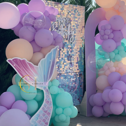 Decorative pastel balloon arrangement with a mermaid tail cutout and a mosaic backdrop that says "Happy 17th Birthday".