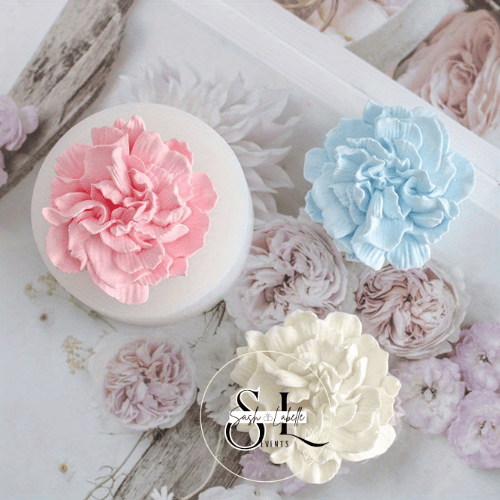 Decorative flowers in pink, blue, and white colors on a white surface with a cake or box.