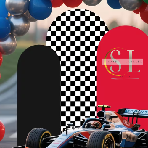 A racing car displayed at an event with a decorative arch made of balloons in blue, silver, red, and green, and a backdrop with black and white checkered and pink arches, featuring a logo for 'Sash Labelle Event'.