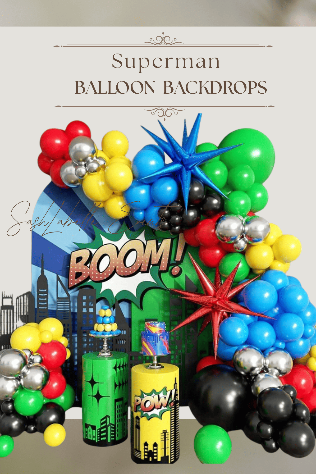 Superman-themed balloon backdrop with cityscape decorations, stars, and comic book style 'BOOM!' and 'POW!' signs.
