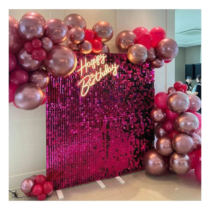 A pink and purple sequin backdrop with a neon sign that reads 'Happy Birthday,' decorated with clusters of pink and metallic rose gold balloons.