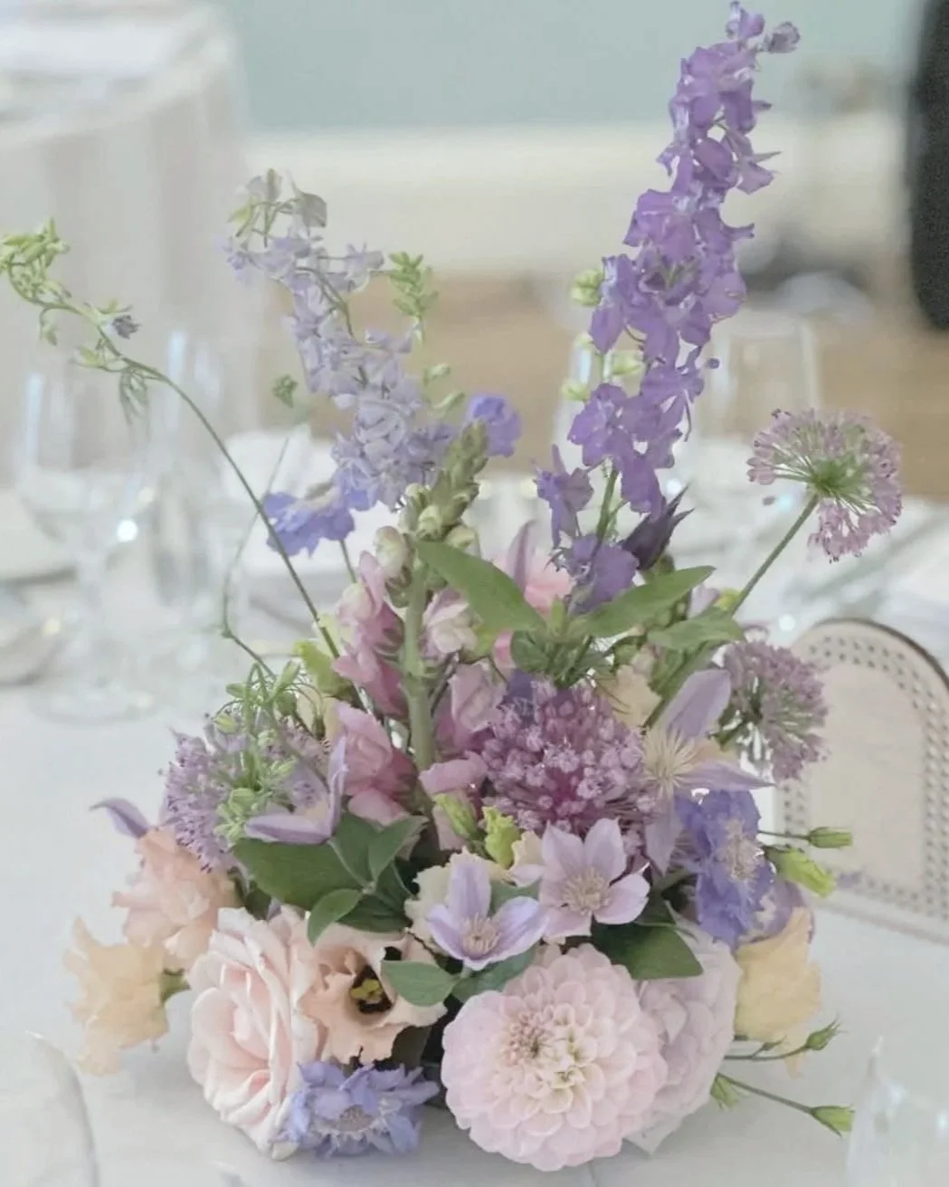 A floral centerpiece with purple, pink, and white flowers on a table at an elegant event.