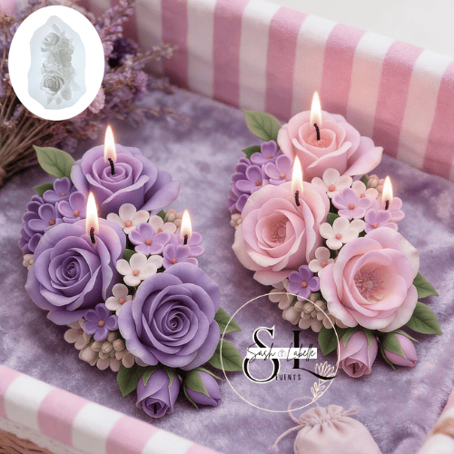 Two floral arrangement candles with purple and pink roses, surrounded by small purple and white flowers, set inside a decorated box.