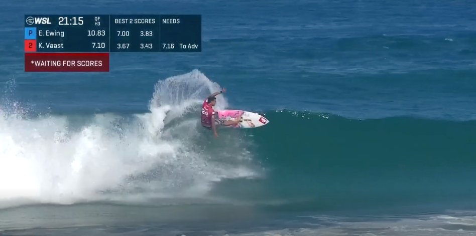 Un surfeur en rouge effectuait une manoeuvre sur une vague dans l'océan, avec un tableau de surf principalement blanc et rose. Écrans affichent des scores de compétition de surf en haut à gauche.