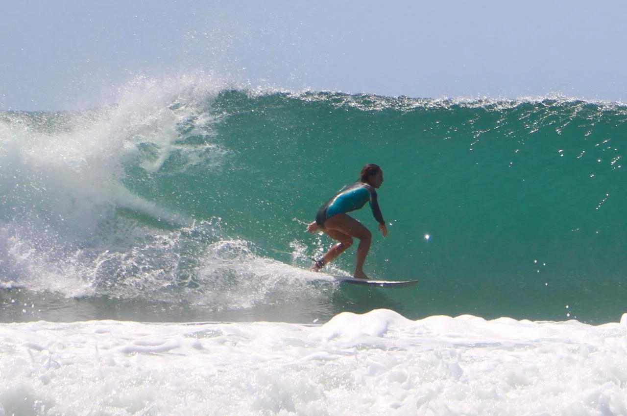 Une femme sur une planche de surf chevauche une vague à la mer