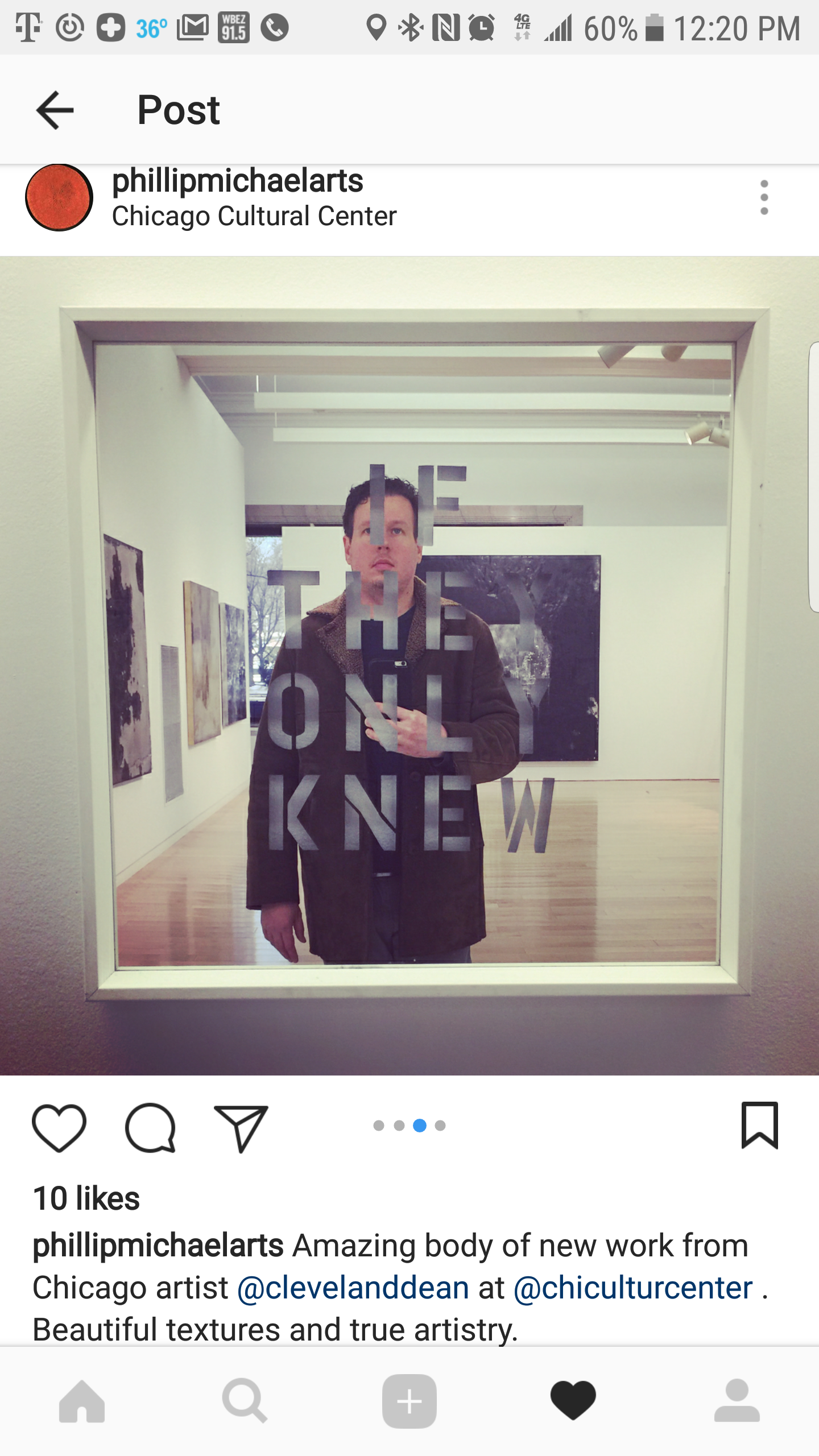 A person taking a mirror selfie inside an art gallery, with artwork visible on the walls behind them and text on the mirror that says, 'IF THEY ONLY KNEW'.