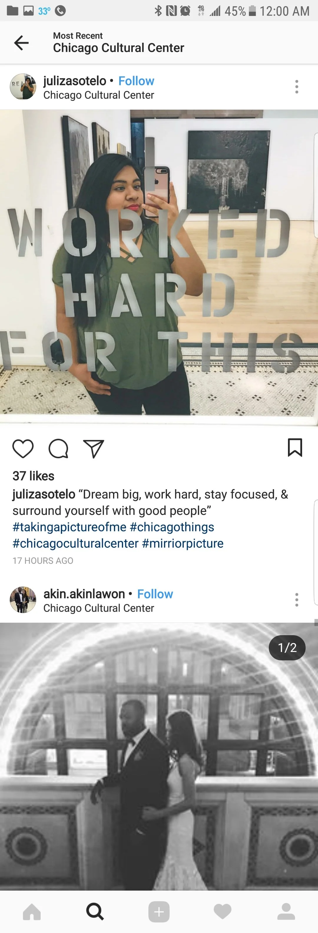 A woman taking a selfie in front of a mirror at the Chicago Cultural Center, with a sign that reads 'WORKED HARD FOR THIS'. She has long black hair and is wearing a green top.