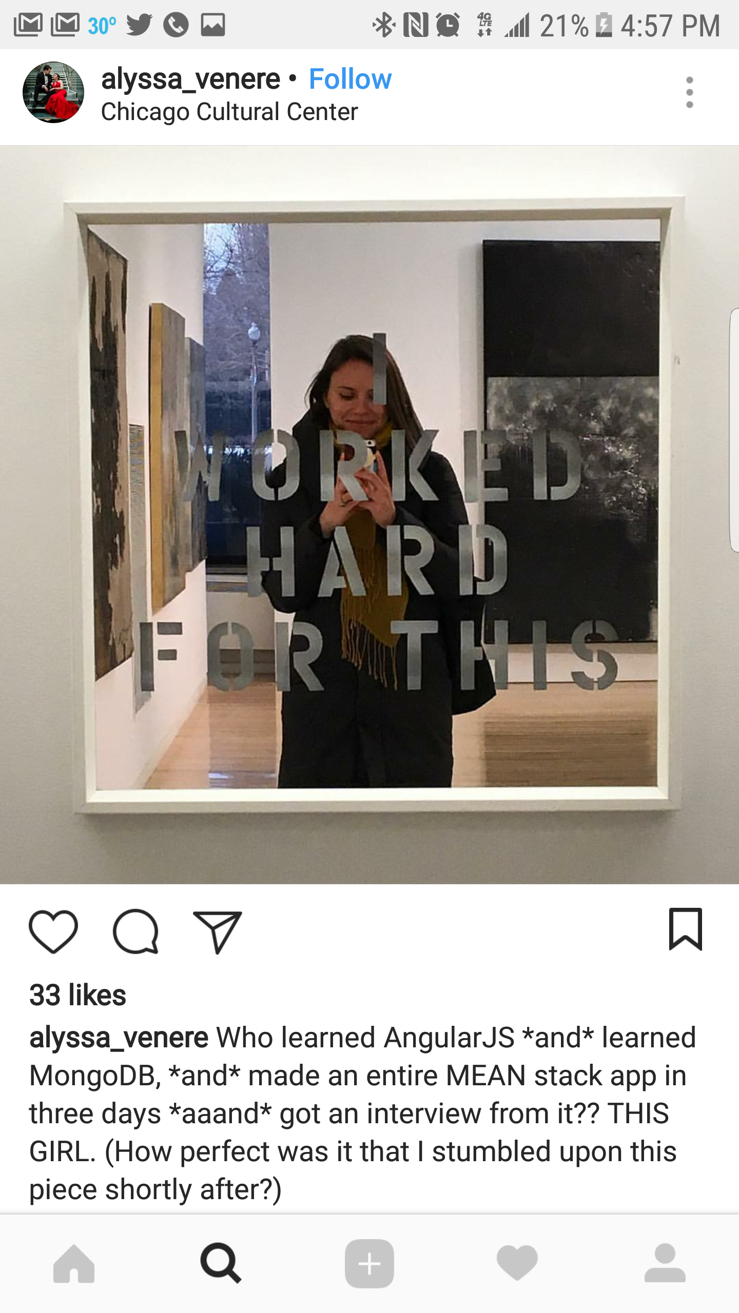 A woman taking a selfie in a mirror at the Chicago Cultural Center, with art on the walls behind her, and the mirror has the phrase 'Worked Hard for This' written on it.
