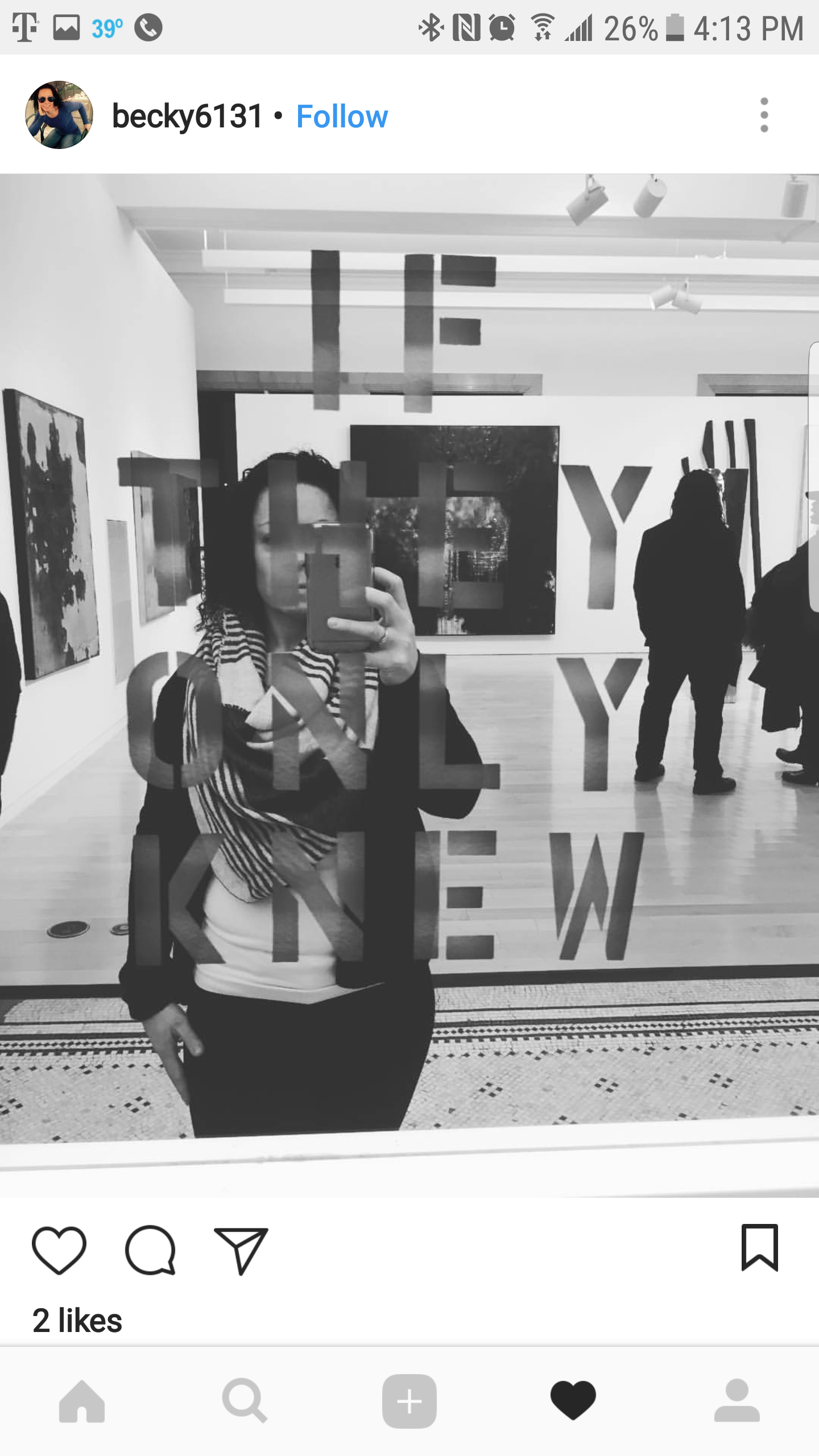 A woman taking a mirror selfie in an art gallery, with the words 'THE NEW' visible on the mirror.