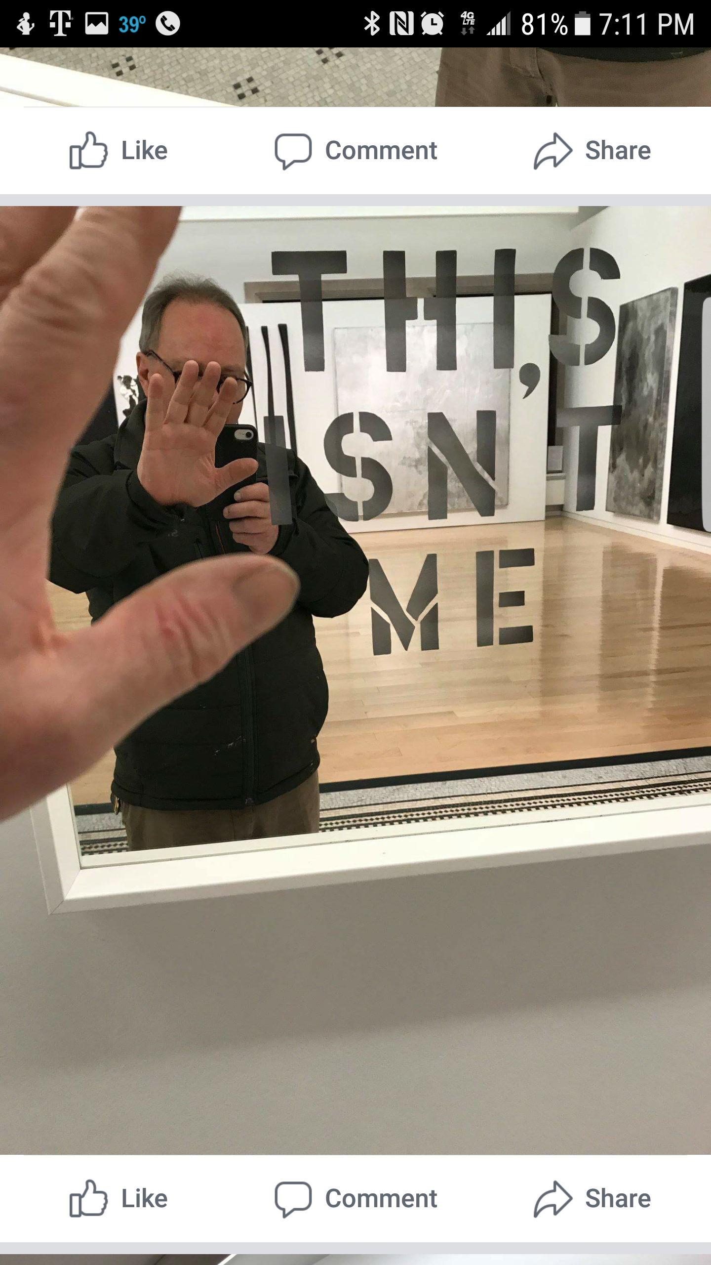 A man taking a selfie in a mirror with the words 'IT, $N'T, ME' on the glass.