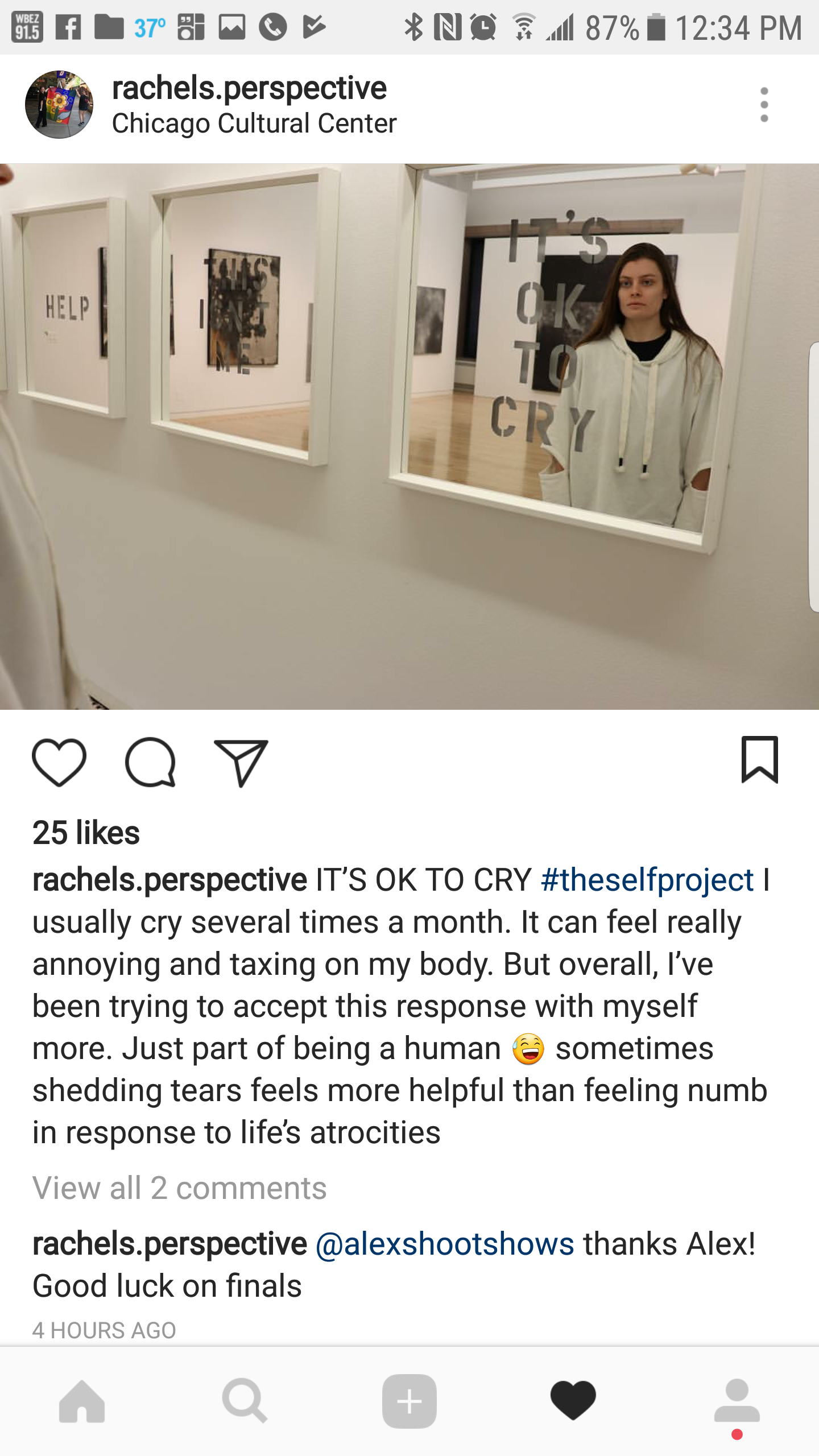 A woman standing in front of a mirror at the Chicago Cultural Center, reflecting her image with text on the mirror saying 'IT'S OK TO CRY'.
