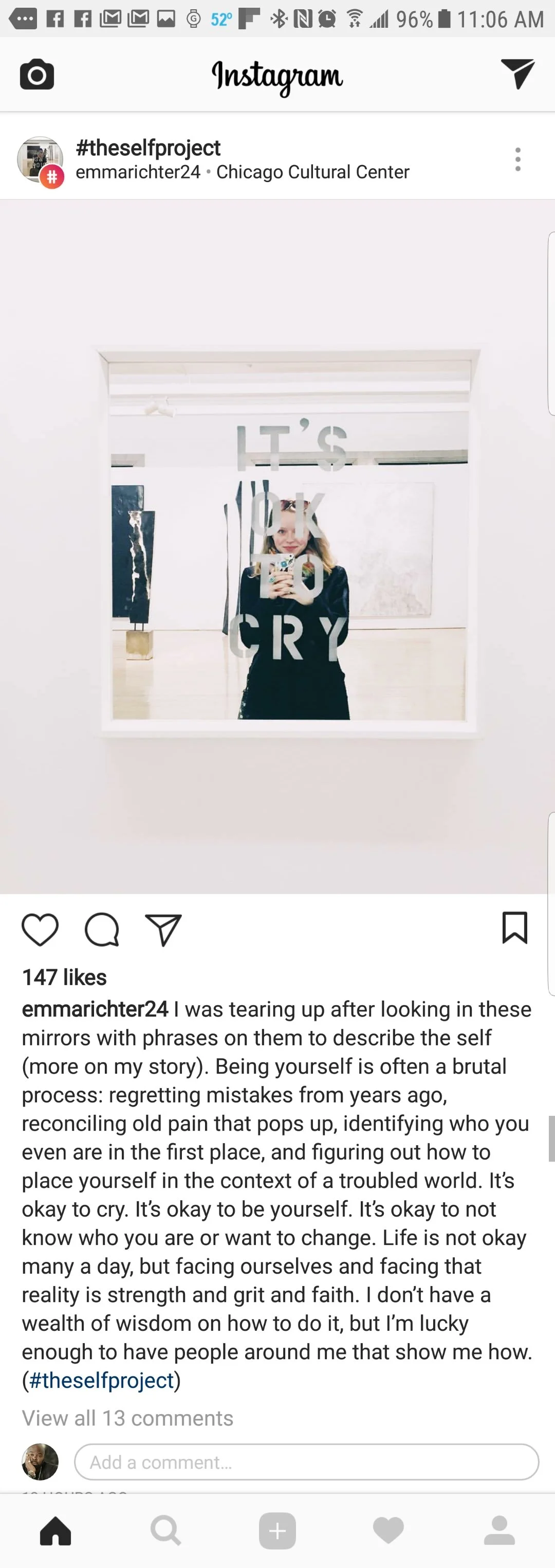 A woman taking a selfie in a mirror with words on it that say 'IT'S OK TO CRY' at Chicago Cultural Center.