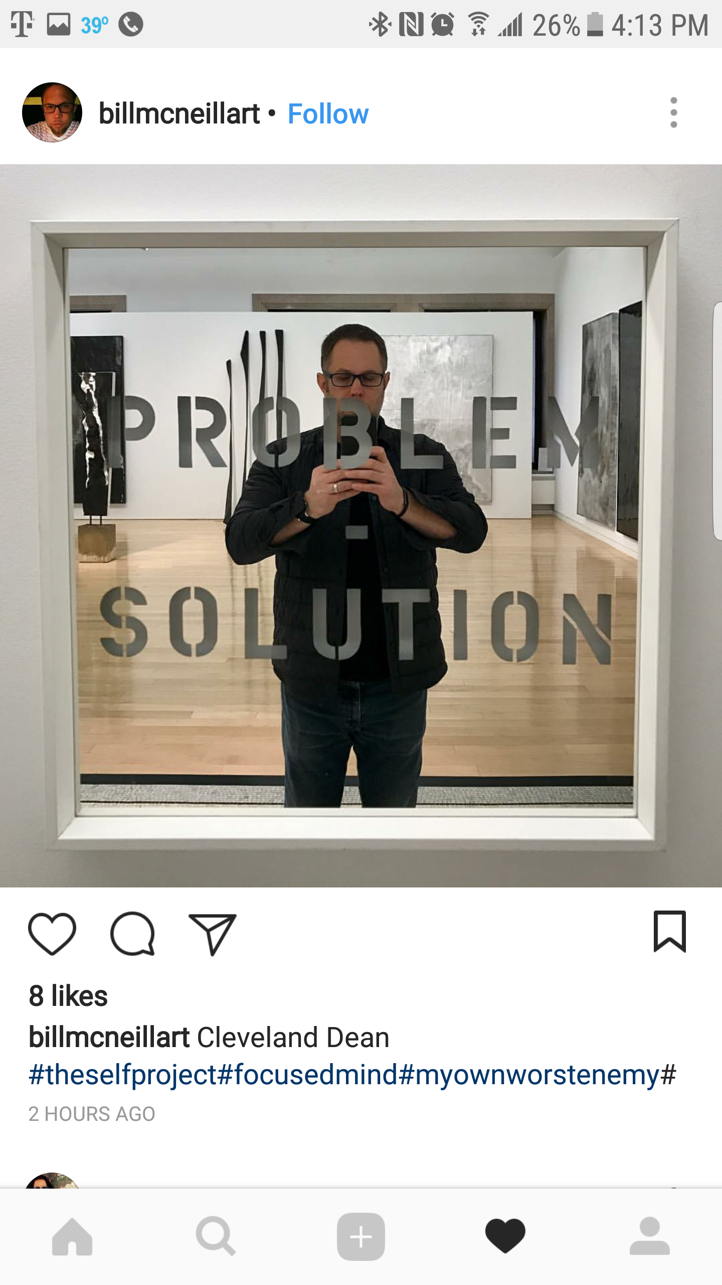 A man is taking a selfie in a mirror with the words "PROBLEM SOLUTION" written on it. Art pieces are visible in a gallery setting in the background.