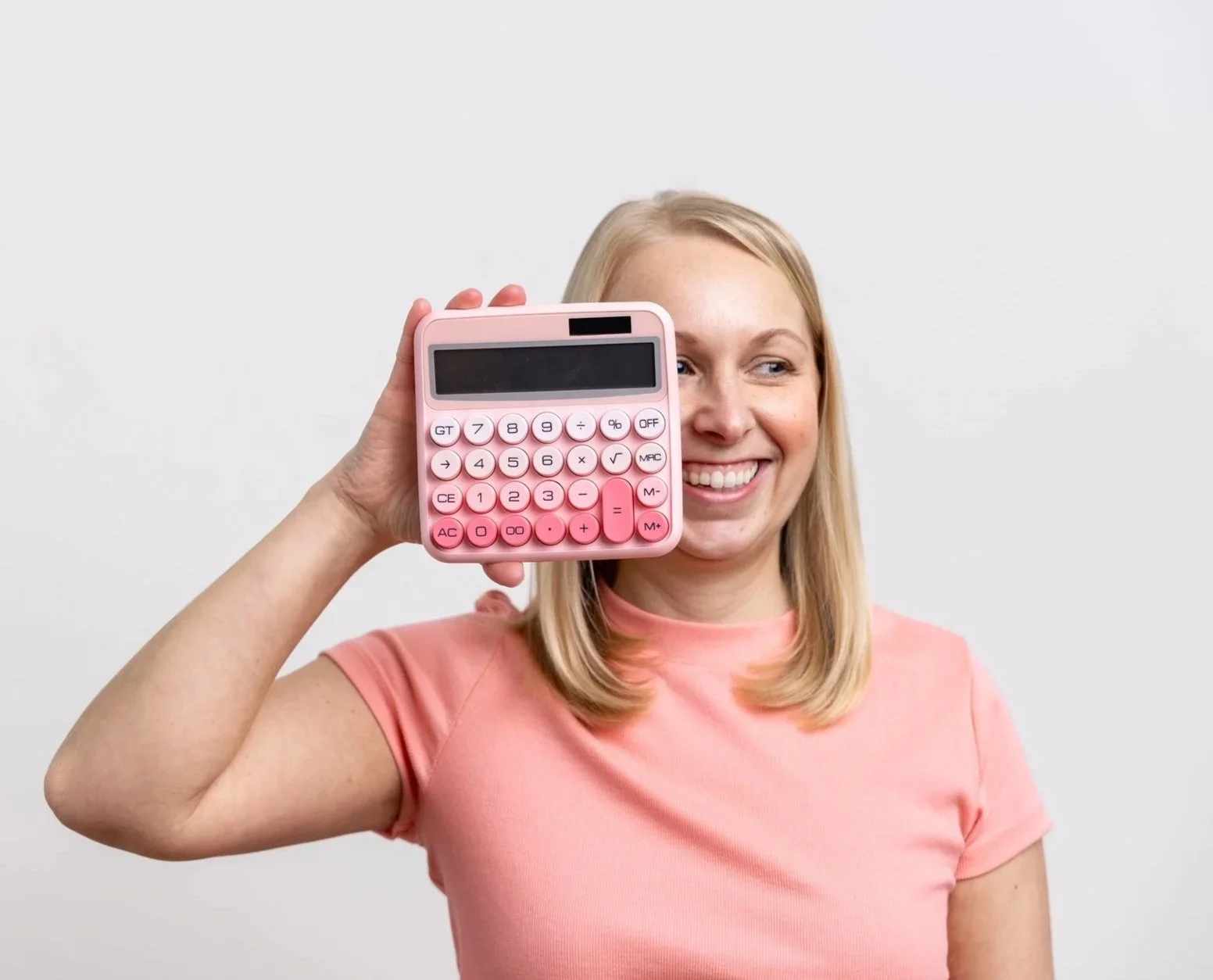 Woman smiling and holding a pink calculator to her ear
