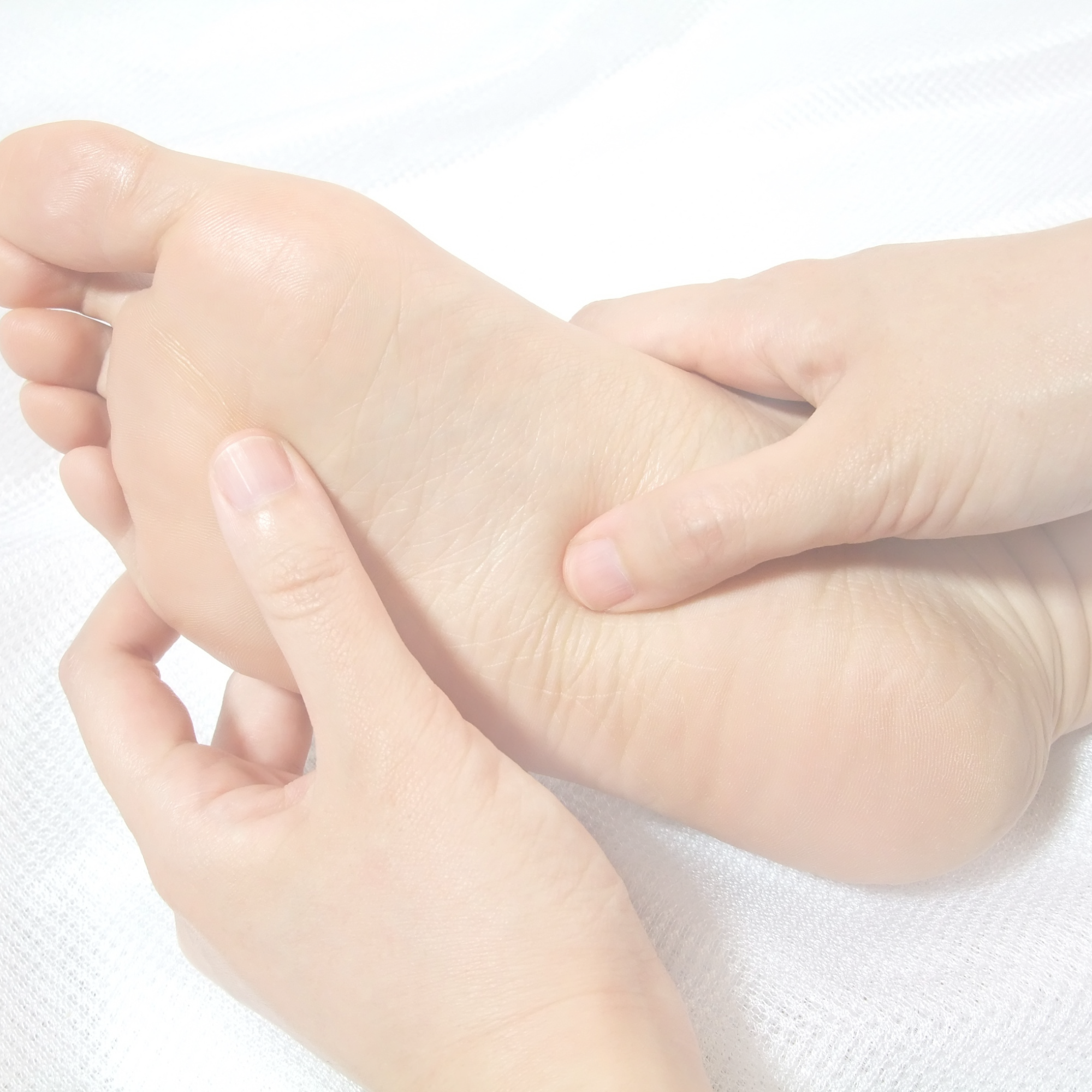 Hands massaging the sole of a foot.