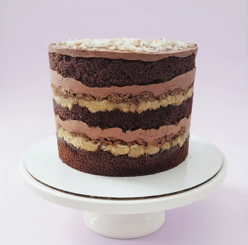Layered chocolate cake, decorated in the naked cake style, on a white cake stand against a light background.